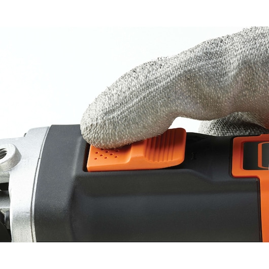 Close-up of a gloved hand pressing the orange switch on a BLACK+DECKER power tool.