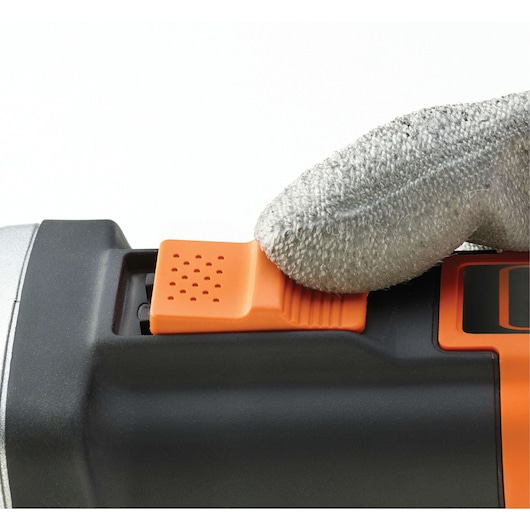 A close-up of a gloved hand operating the orange power switch on a BLACK+DECKER tool.