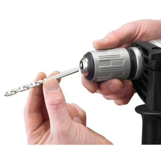 Close-up of hands inserting a drill bit into the chuck of a BLACK+DECKER power drill.