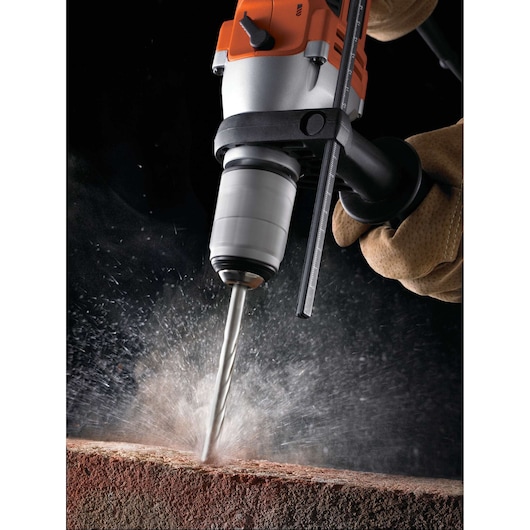 BLACKDECKER KR805K hammer drill in use drilling into masonry, close-up with dust and debris flying.