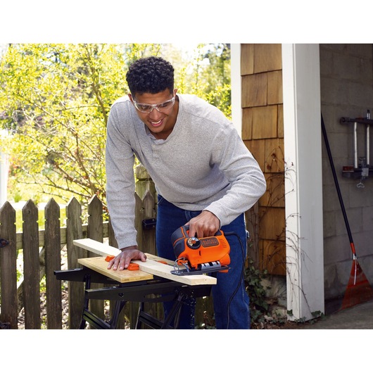 BLACKDECKER KS801SE jigsaw used for cutting wood outdoors on a workbench.