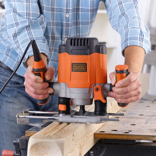 BLACK+DECKER KW1200EKA router tool in use on wooden board, close-up front angle.