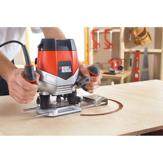 BLACKDECKER KW900EKA wood router in use cutting a curved groove on plywood, workshop background.