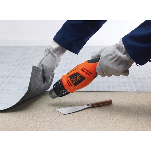 BLACKDECKER KX1693 orange heat gun in use for flooring removal, with gloves and metal scraper visible.