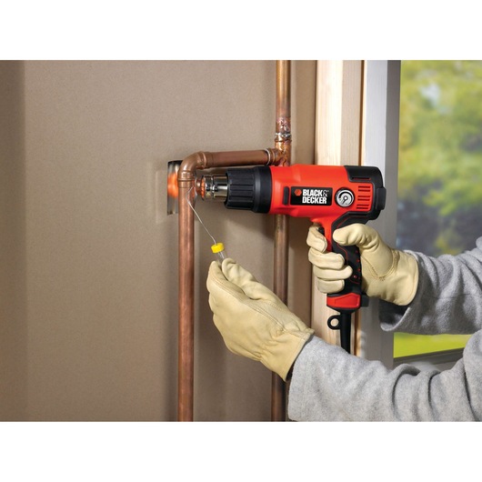 BLACKDECKER KX2200K heat gun used on copper pipes, person wearing gloves.