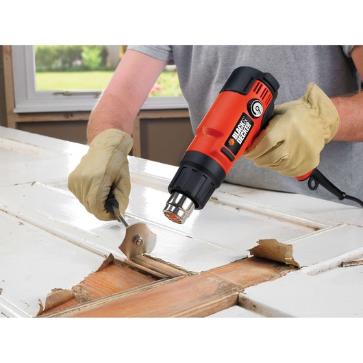 BLACKDECKER KX2200K heat gun used to strip paint from wooden door, close-up photography.