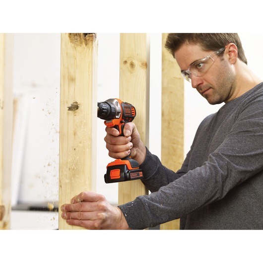 Photo of BLACKDECKER MT218K cordless drill in use drilling through wood, orange and black design.