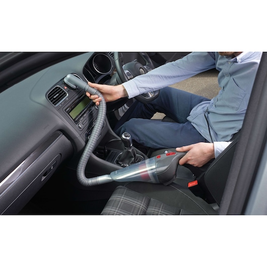 BLACK+DECKER NV1210AV handheld vacuum cleaner used for car interior cleaning, flexible hose attachment visible.