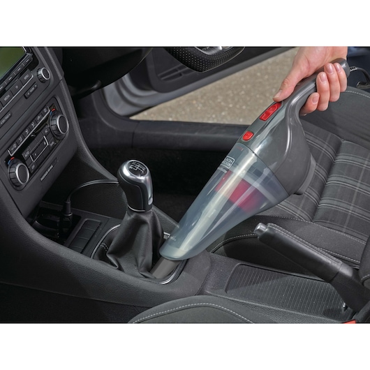 Photo of BLACK+DECKER NV1210AV handheld vacuum being used to clean a car interior around the gear shift.