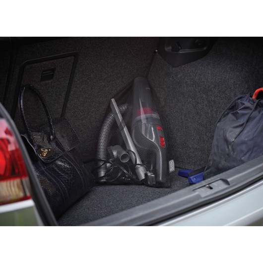 BLACKDECKER NV1210AV handheld vacuum cleaner in a car trunk with accessories and bags.