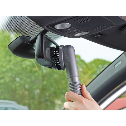 BLACKDECKER NV1210AV vacuum brush cleaning car rear view mirror, close-up showing hand and detail.