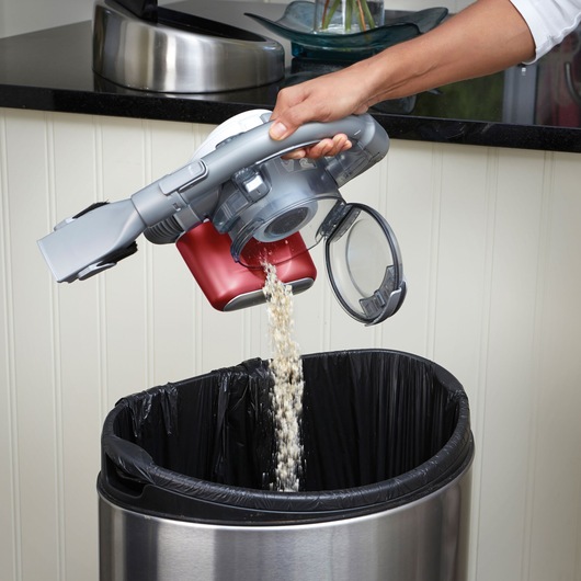 BLACKDECKER PD1020L handheld vacuum being emptied into a trash can, shown with open dustbin and red body.