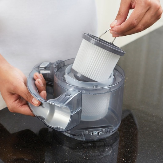 BLACKDECKER PD1020L vacuum filter being removed from clear canister on dark countertop.