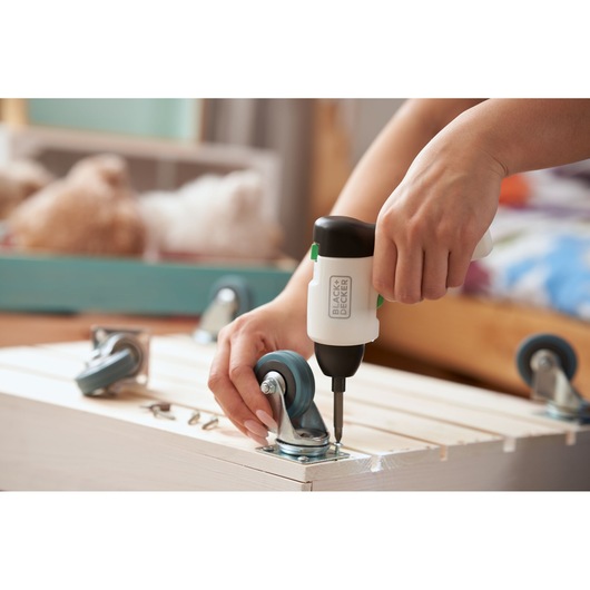 Photo of BLACKDECKER REVSD4C cordless screwdriver assembling caster wheels on a wooden crate.