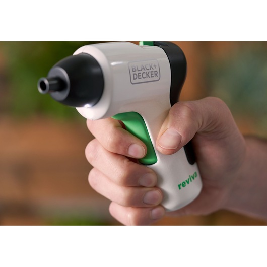 Close-up photo of BLACK+DECKER REVSD4C cordless screwdriver in hand, white with green trigger, reviva logo visible.