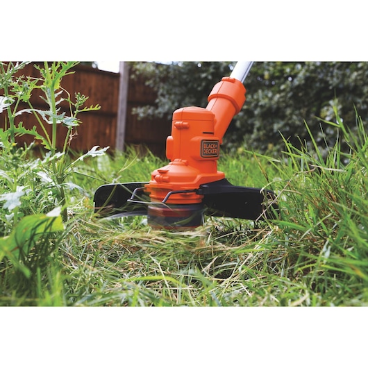 BLACKDECKER ST4525 grass trimmer close-up photo cutting tall grass outdoors.