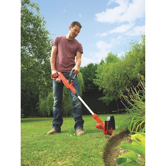 BLACKDECKER ST4525 grass trimmer with red and black body used for edging lawn in garden.