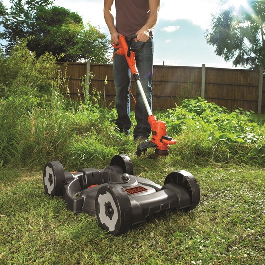BLACKDECKER ST5530CMCAK lawn mower and trimmer in garden setting with grass and wooden fence