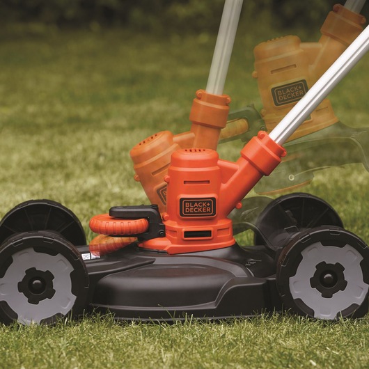 BLACKDECKER ST5530CMCAK lawn mower base, close-up side view showing adjustable handle on grass.