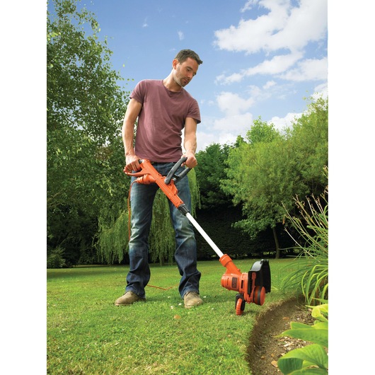 Photo of BLACKDECKER ST5530 grass trimmer with orange and black design used for edging lawn.
