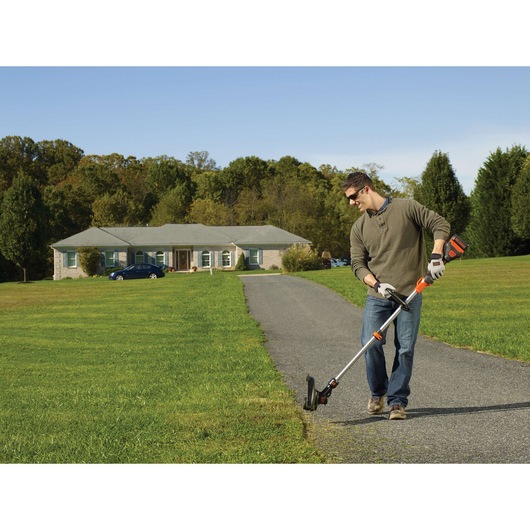 BLACKDECKER STB3620L grass trimmer in use on lawn edge near driveway, outdoor setting.