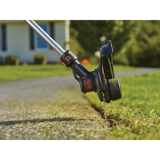 BLACKDECKER STB3620L cordless grass trimmer edging along a lawn and sidewalk