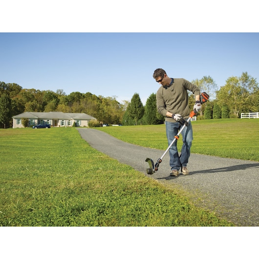 BLACKDECKER STB3620L cordless string trimmer used on lawn near driveway, outdoor setting.
