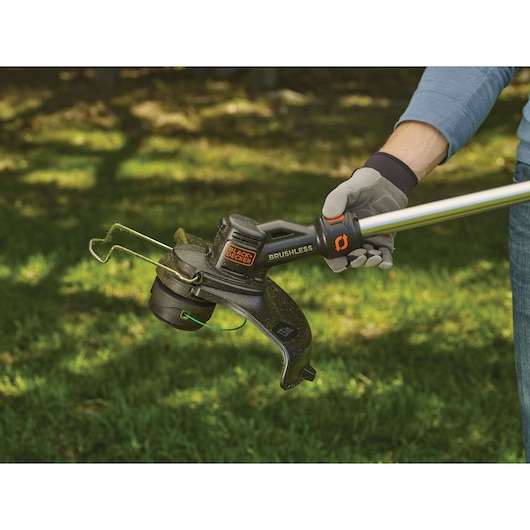 Photo of BLACK+DECKER STB3620L brushless string trimmer being used outdoors, close-up of cutting head.