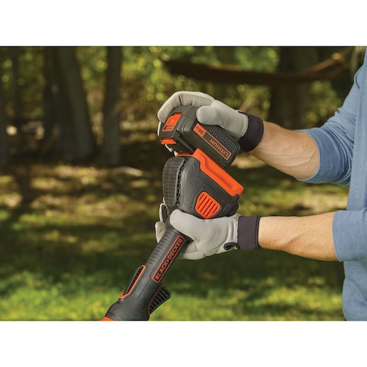 Photo of BLACKDECKER STB3620L cordless garden tool with 36V lithium battery being installed, close-up outdoor view.