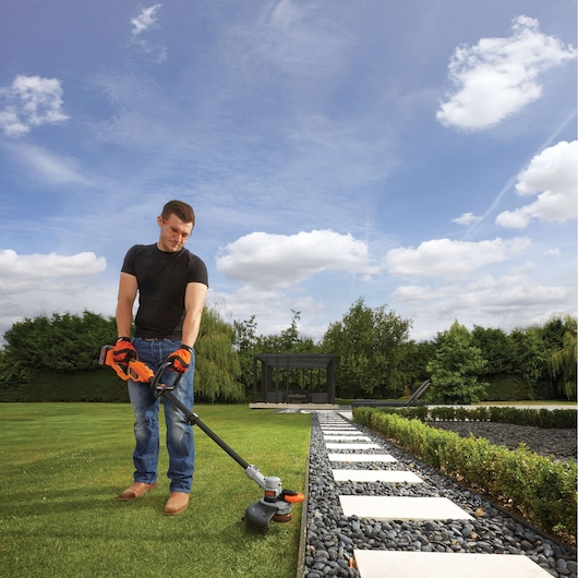 BLACKDECKER STC1840PC grass trimmer in use on garden lawn, orange and black design, photography outdoors