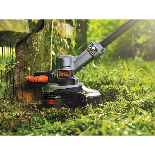BLACK+DECKER STC1840PC grass trimmer closeup cutting edge grass outdoors.