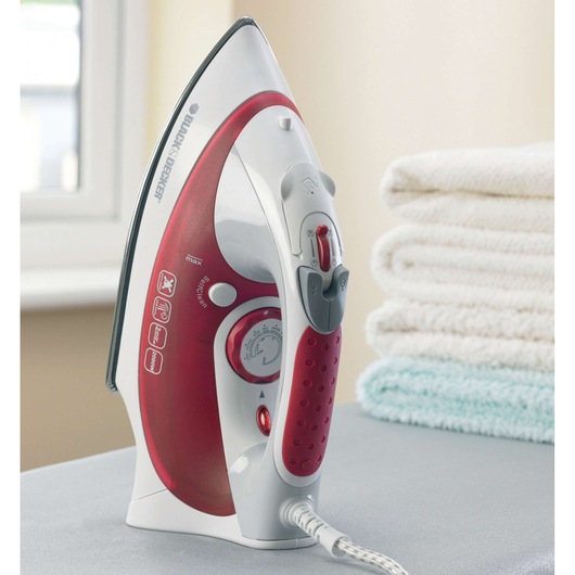 BLACKDECKER XT2040 steam iron in red and white, upright on ironing board, towels stacked nearby