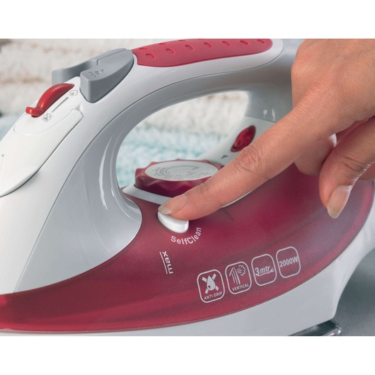 Photo of BLACKDECKER XT2040 steam iron close-up, showing hand pressing SelfClean button, red and white design.