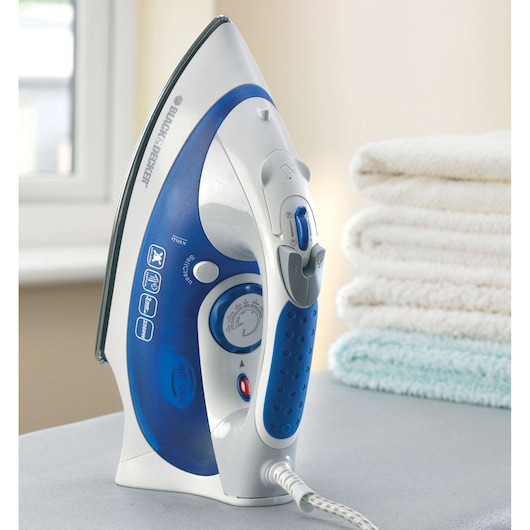 BLACK+DECKER XT2200 steam iron in blue and white, upright on table near folded towels, side angle.