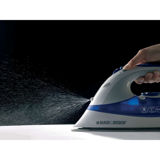Photo of BLACK+DECKER XT2200 steam iron spraying water, side view, with dark background.